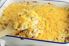 a wooden spoon scooping out some food from a casserole in a blue and white dish