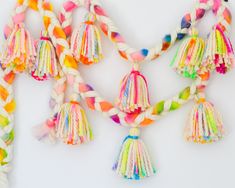 multicolored tassels are hanging on a white wall and one is made out of rope