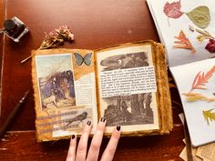 a woman's hand is holding an open book with pictures and leaves on it