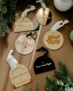 several tags and pine branches on a table with christmas decorations around them, including one for rofee