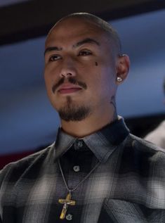 a close up of a person wearing a shirt with a cross on the chest and necklace