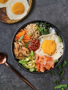 a bowl filled with rice, meat and vegetables next to an egg on top of it