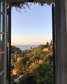 an open window looking out at the ocean and trees in front of it on a sunny day