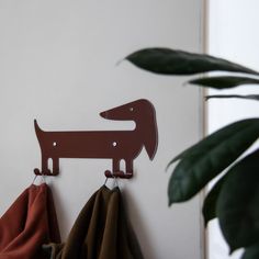 a coat rack with two hooks on it and a red dog hanging from the wall