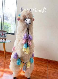 a white llama with multicolored tassels on it's back