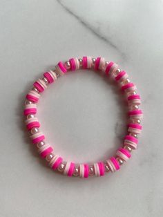 the pink and white beaded bracelet is sitting on a marble counter top, with silver beads