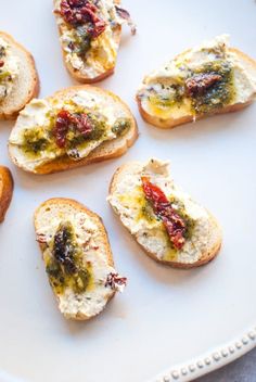 several pieces of bread with cheese and toppings on them sitting on a white plate