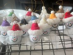 small knitted snowman ornaments are sitting on a wire rack