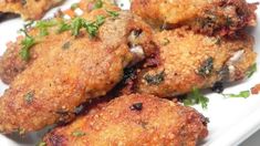 some fried food on a white plate with parsley sprinkled around the edges