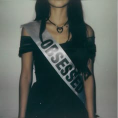 a woman in a black dress with a silver sash