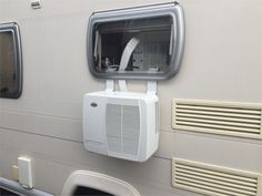 an air conditioner mounted on the side of a white motor home with two windows