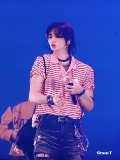 a woman in pink shirt and black shorts on stage with cell phone up to her ear