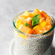 a glass bowl filled with chia pudding topped with orange slices and mint leafy garnish