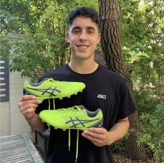 a young man holding two soccer shoes in his hands