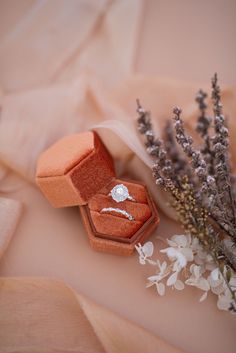 an open ring box sitting on top of a table next to lavenders and flowers