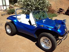 a blue dune buggy is parked in the dirt