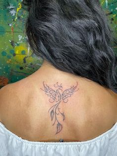 the back of a woman's neck with an angel tattoo on her left shoulder