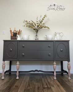 an old dresser with some flowers on top and other items sitting on the sideboard