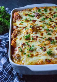 a casserole dish with cheese, meat and parsley on the side next to broccoli