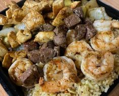 a tray filled with rice and shrimp next to meat on skewered veggies