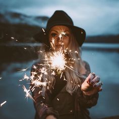 a woman holding sparklers in her hand and looking at the camera with an instagramr