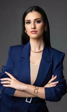 a woman with her arms crossed wearing a blue suit