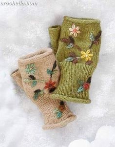 two knitted mittens sitting on top of snow covered ground