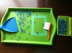 a green tray with blue beads and a toothbrush sitting on top of it next to a plastic container