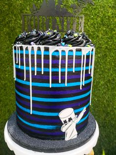 a black and blue striped cake with white icing on it's top tier