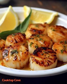 a white plate topped with scallops and lemon wedges