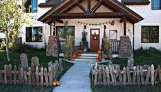 a white house with pumpkins on the front lawn and fenced in yard area