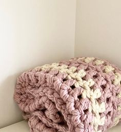 a pink and white crocheted blanket sitting on top of a table