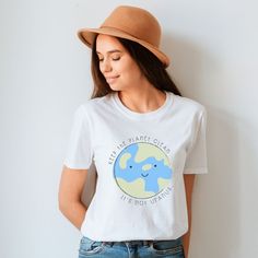 a woman wearing a white t - shirt with an elephant on it and a brown hat