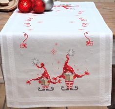 the table is decorated with red and silver decorations, including two christmas ornaments on top of it