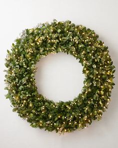 a green wreath with white lights hanging on the wall