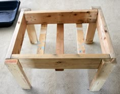 a wooden bench sitting on top of a carpeted floor next to a black tray