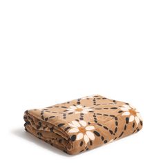 a brown blanket with black and white flower designs on it, folded to the side