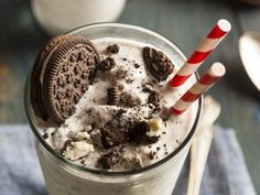 an oreo cookie milkshake in a tall glass with a candy cane on top