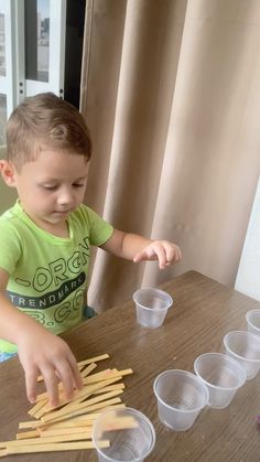 a little boy that is sitting at a table with some sticks in front of him