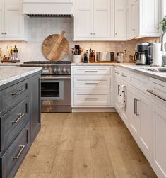 a kitchen with white cabinets and wood floors is pictured in this image, there is a large wooden cutting board on the wall above the stove