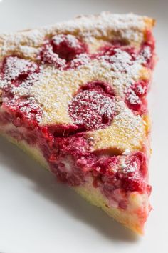 a piece of cake with powdered sugar on top and raspberries in the middle