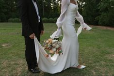 a bride and groom standing in the grass