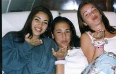 three young women laying in bed with one pointing at the camera and the other smiling