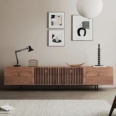 a living room with pictures hanging on the wall and a wooden cabinet in front of it