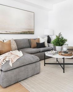 a living room filled with furniture and a large painting on the wall above it's coffee table