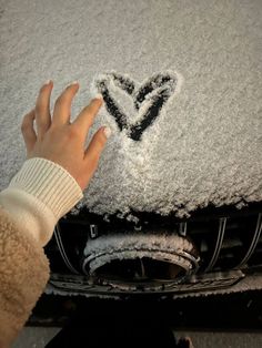 someone's hand on the hood of a car covered in snow