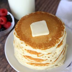 a stack of pancakes with butter and berries on the side