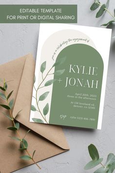 a green and white wedding card on top of envelopes with greenery in the background