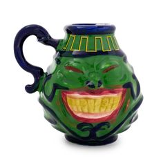 a green and blue ceramic jug with a smiling face