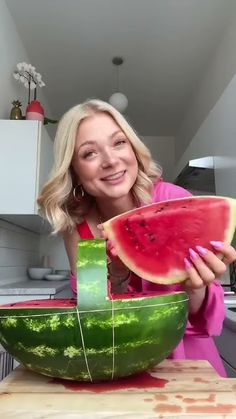 a woman holding a piece of watermelon in her hand